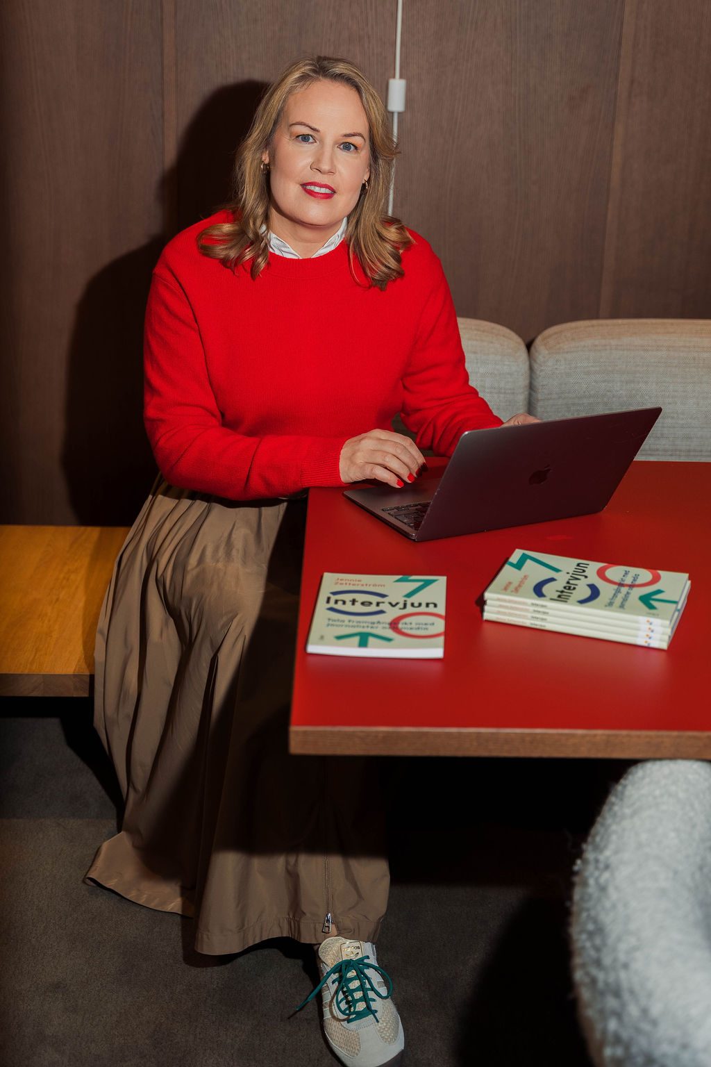 Jennie Zetterström vid ett bord med datorn och boken Intervjun